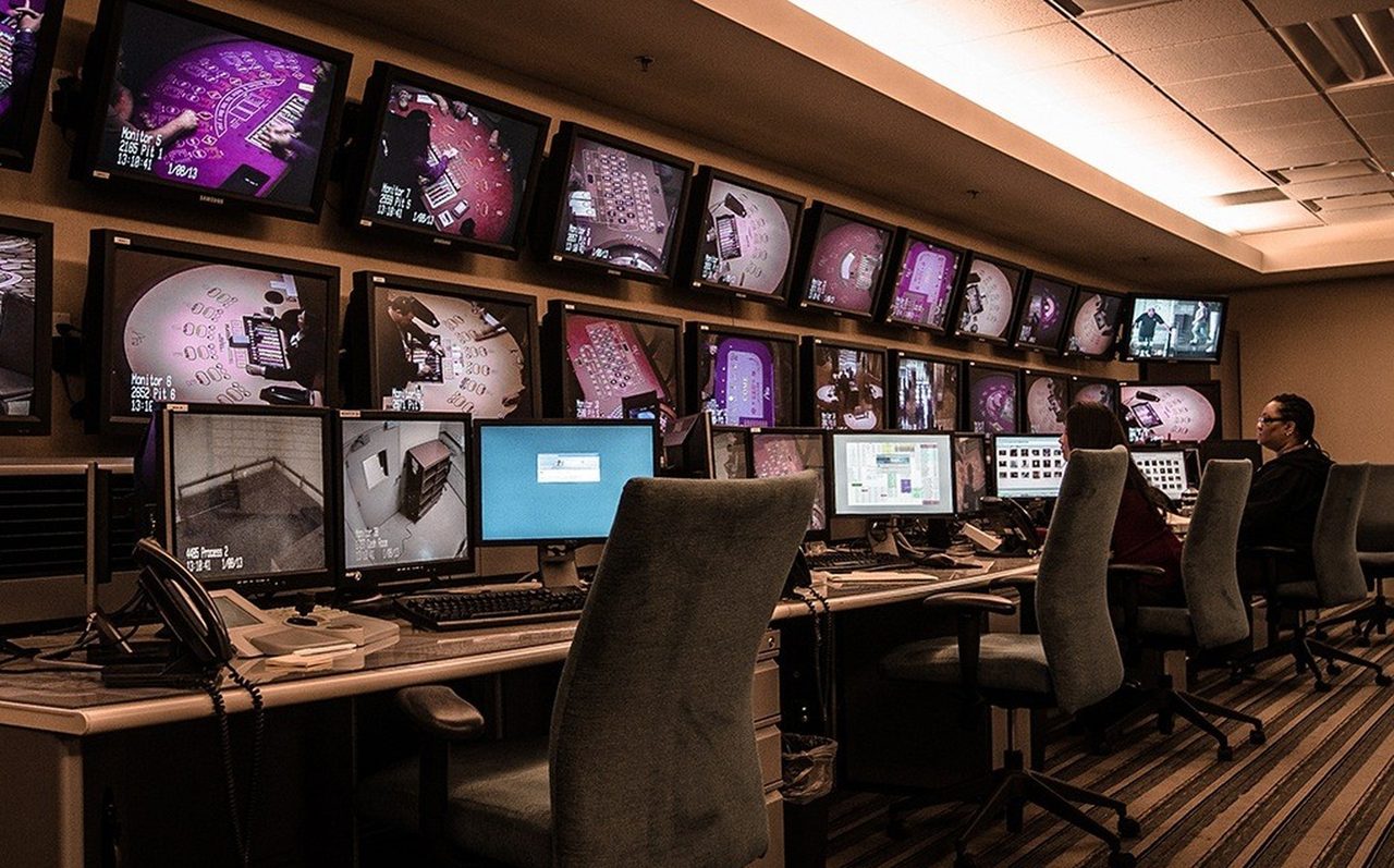 A surveillance control desk with a wall of monitors.